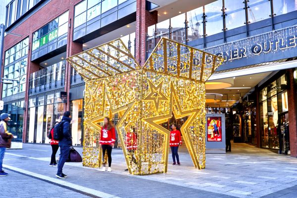 outside a shopping mall there's a giant lighting christmas gift