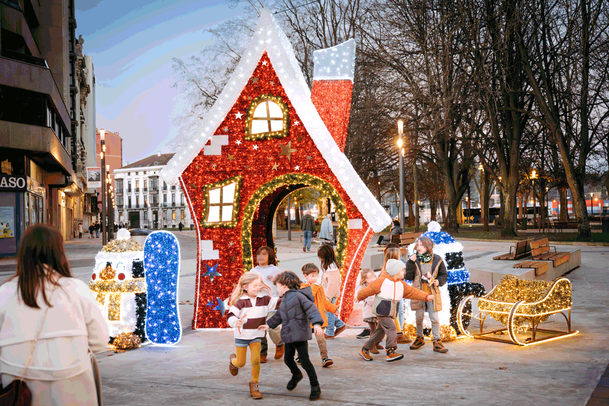 children playing in a square with giant light decorations in shape of a red house and penguins