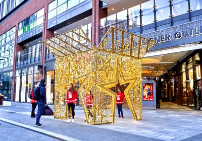 outside a shopping mall there's a giant lighting christmas gift