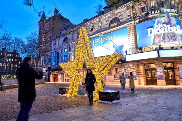 people taking pictures with a giant lighting star in front of a theatre