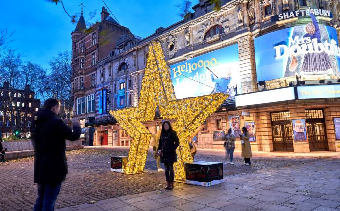 people taking pictures with a giant lighting star in front of a theatre