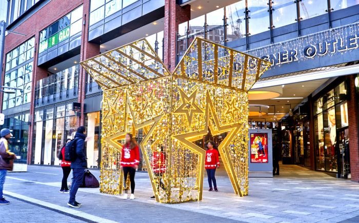 outside a shopping mall there's a giant lighting christmas gift
