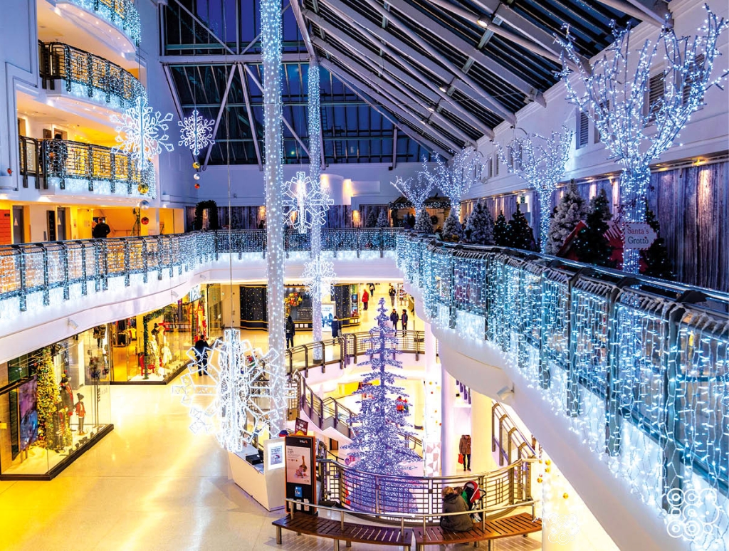 inside a shopping centre with balconies and trees decorated with Christmas lights