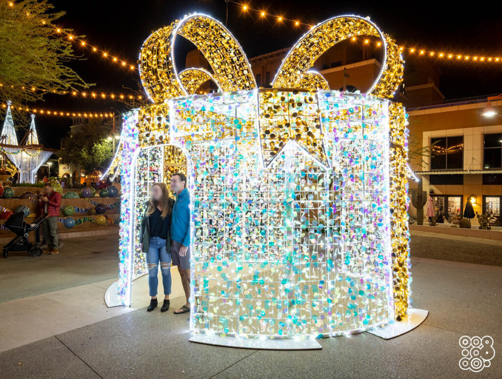 giant 3D illuminated chritmas gift with a couple inside that thakes a picture