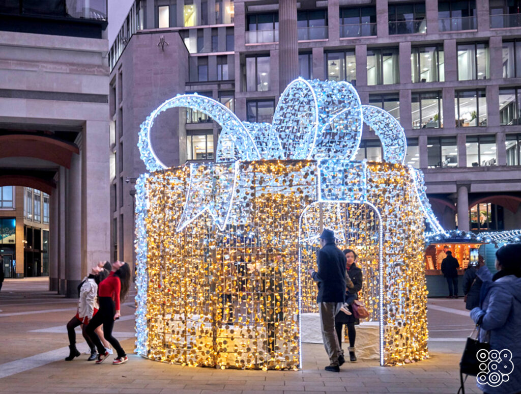 people taking pictures with a giant lighting gift box