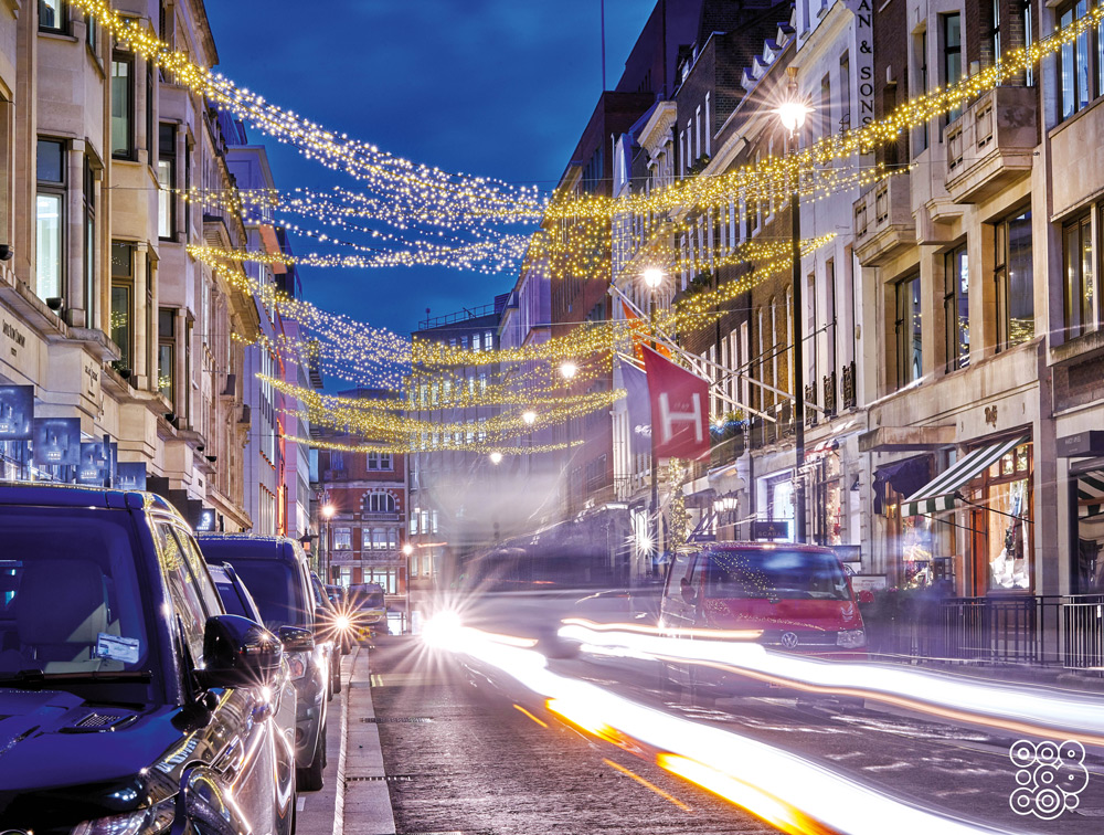 street with carts parked inthe sides and led strings as Christmas decorations